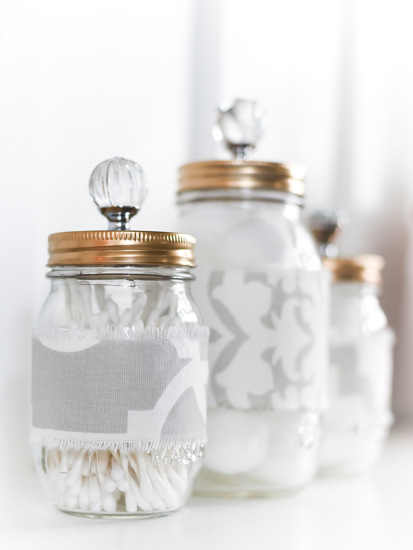 Fabric Covered Mason Jars with Gold Spray Painted Lids and Crystal Knobs.