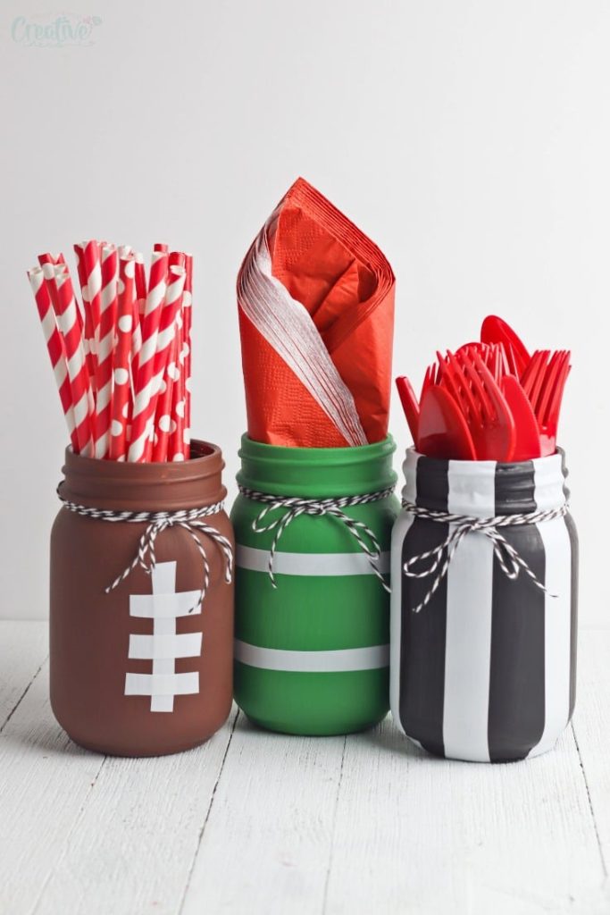 Football Mason Jar Crafts & Party Ideas. Football Party with Mason Jars. Mason Jar Football Centerpiece. Mason jar football drink cups. Mason jar football utensil holder.