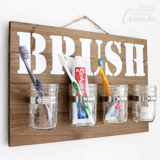 Rustic mason jar toothbrush station. Hanging toothbrush storage for bathrooms. Mason Jar Bathroom Storage and Organization Ideas. Organizing the bathroom with mason jars. Pretty storage ideas with mason jars. Rustic storage ideas with mason jars. Bathroom storage using mason jars.