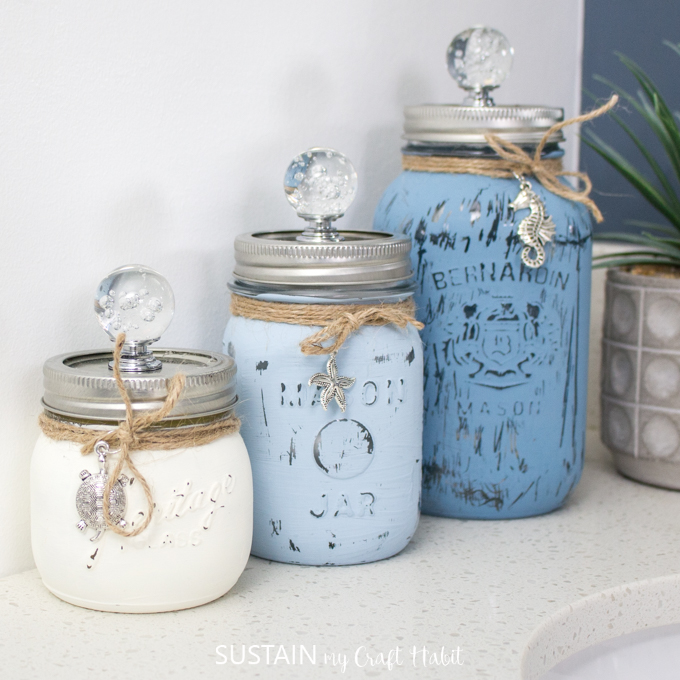 Beachy Painted and Distressed Mason Jar Bathroom Organizers. Mason Jar Bathroom Storage and Organization Ideas. Organizing the bathroom with mason jars. Pretty storage ideas with mason jars. Rustic storage ideas with mason jars. Bathroom storage using mason jars.