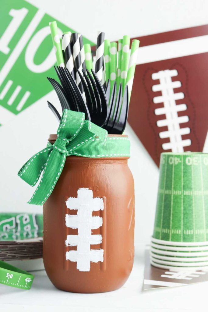 Football Mason Jar Crafts & Party Ideas. Football Party with Mason Jars. Mason Jar Football Centerpiece. Mason jar football drink cups. Mason jar football utensil holder.