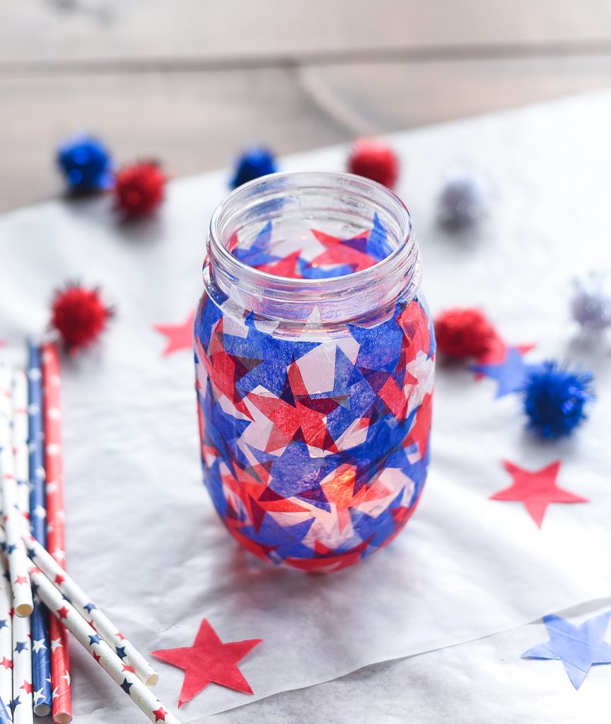 Red White Blue Tissue Paper Decoupage Mason Jar. Decoupage Stars on Mason Jars. Kid's Craft for Fourth of July with Mason Jars. Fourth of July Mason Jar Crafts and Decor Ideas. Red, White and Blue Mason Jars. Patriotic Mason Jars. Semiquincentennial Mason Jars to Celebrate 4th of July. July 4 Decor Ideas with Mason Jars.